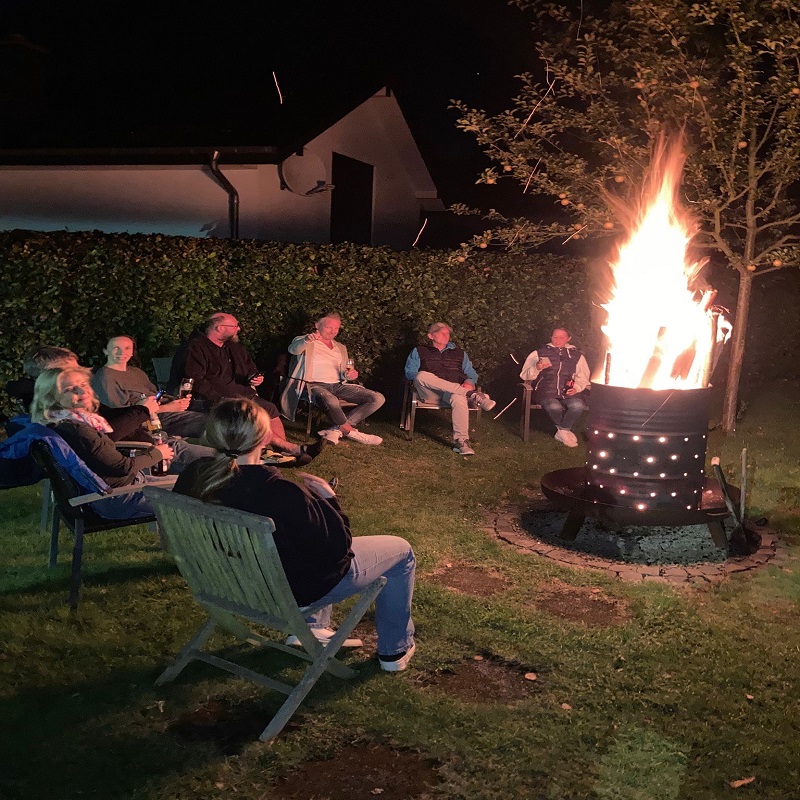 Menschen sitzen um eine brennende Feuertonne