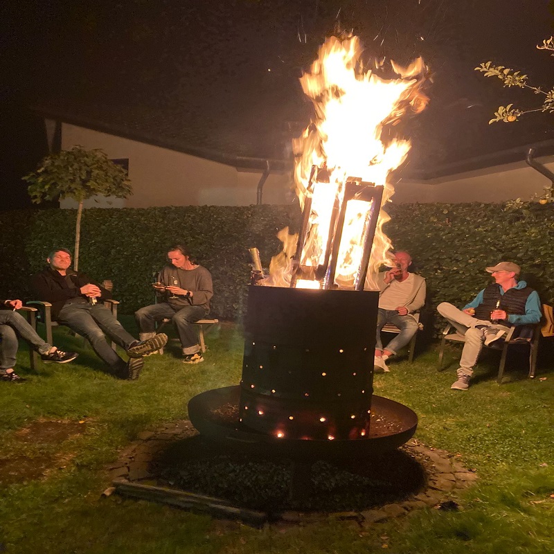 Menschen sitzen um eine brennende Feuertonne